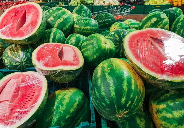 Granja fresca, dulce y natural cultivada, rodajas de frutas orgánicas tropicales de sandía con cortezas verdes duras, carne jugosa rojiza y muchas semillas negras en la naturaleza. Fruta asiática estacional en el mercado callejero de alimentos — Foto de Stock