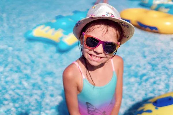Mała dziewczynka w okularach przeciwsłonecznych i kapeluszu z jednorożcem w odkrytym basenie luksusowego kurortu na letnie wakacje na tropikalnej wyspie plaży — Zdjęcie stockowe