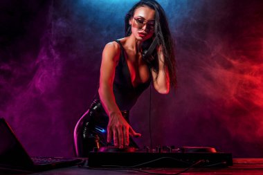 Genç seksi kadın dj müzik çalma. Kulaklıklar ve dj mixer masada.