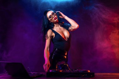 Genç seksi kadın dj müzik çalma. Kulaklıklar ve dj mixer masada.