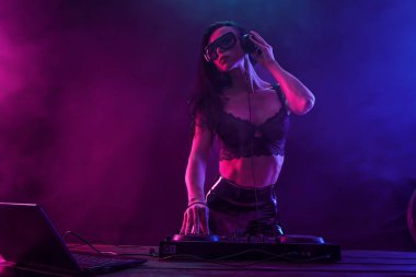 Genç seksi kadın dj müzik çalma. Kulaklıklar ve dj mixer masada.
