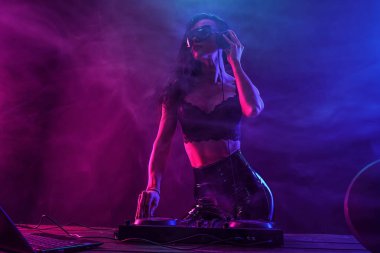 Genç seksi kadın dj müzik çalma. Kulaklıklar ve dj mixer masada.