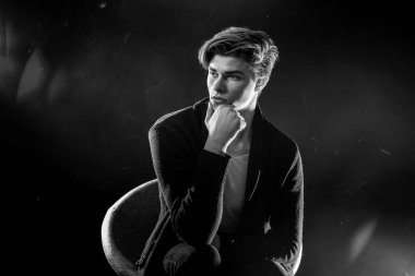 Siyah ceketli ve güneş gözlüklü havalı bir adam. Siyah arka planda poz veren yüksek moda erkek model..