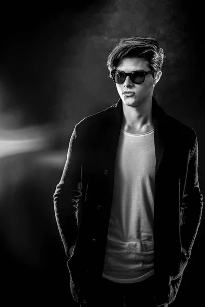 Cool stylish man in black jacket and sunglasses. High Fashion male model posing on black background. — Stock Photo, Image