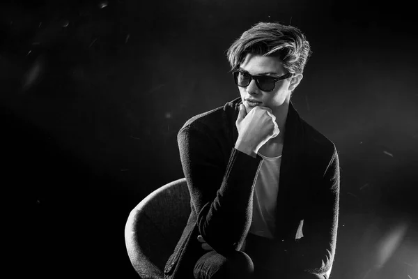 Cool stylish man in black jacket and sunglasses. High Fashion male model posing on black background. — Stock Photo, Image