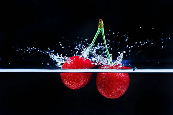 Cherry in sparkling water on black background — Stock Photo, Image