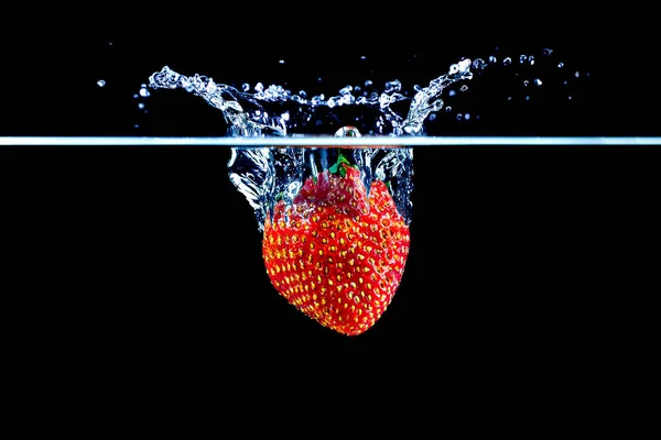 Eine Erdbeere, die ins Wasser spritzt — Stockfoto