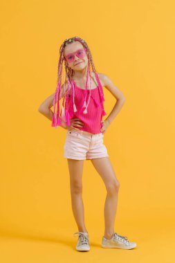 Pembe rastalı ve sarı arka planda poz veren şık bir kız. Güzellik, moda.