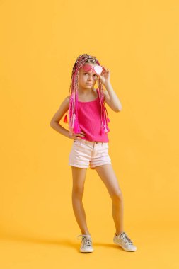 Pembe rastalı ve sarı arka planda poz veren şık bir kız. Güzellik, moda.