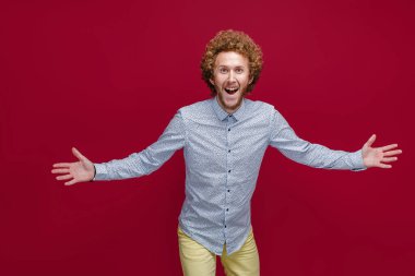 Zarif bir gömlek giyen genç, kıvırcık, olgun bir adam zaferi ya da başarıyı kutluyor, şaşırıyor ve şok oluyor.