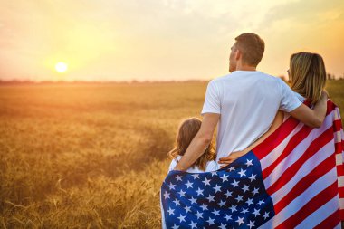 Tanımlanamayan mutlu bir ailenin Amerika ve Amerikan bayrağıyla arka planda buluşması.