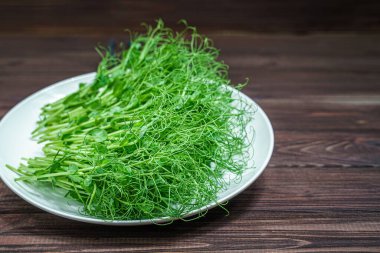 Tahta yüzeyde taze bezelye mikroyeşil lahanalar.