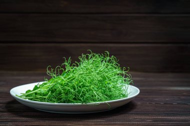 Tahta yüzeyde taze bezelye mikroyeşil lahanalar.