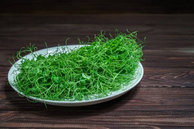 Tahta yüzeyde taze bezelye mikroyeşil lahanalar.