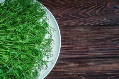 Ahşap yüzeyde taze bezelye ve mikroyeşil lahanaların üst görüntüsü.