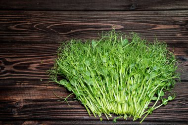 Eski ahşap masada kesilmiş mikro yeşil bezelye filizi. Vejetaryen ve sağlıklı beslenme konsepti. Büyüyen filizler