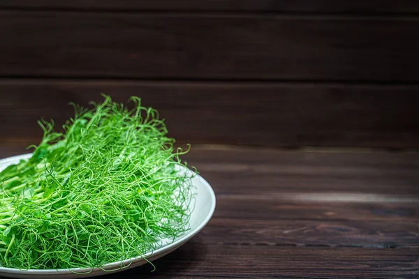 Brotes microverdes de guisante fresco cortado en placa en la superficie de madera — Foto de Stock