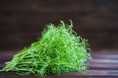 Eski ahşap masada kesilmiş mikro yeşil bezelye filizi. Vejetaryen ve sağlıklı beslenme konsepti. Büyüyen filizler