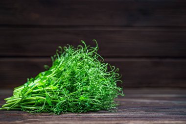 Eski ahşap masada kesilmiş mikro yeşil bezelye filizi. Vejetaryen ve sağlıklı beslenme konsepti. Büyüyen filizler