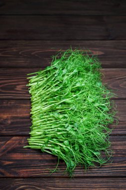 Eski ahşap masada kesilmiş mikro yeşil bezelye filizi. Vejetaryen ve sağlıklı beslenme konsepti. Büyüyen filizler