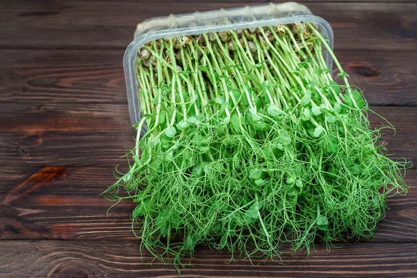 Brotes de guisantes microverdes en mesa de madera. Concepto de alimentación vegana y saludable. Crecimiento de brotes — Foto de Stock