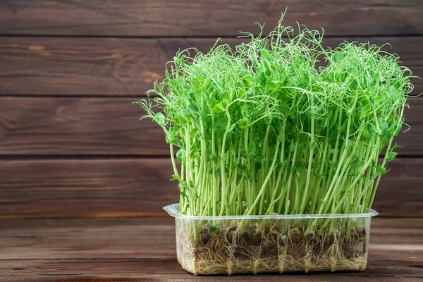 Brotes de guisantes microverdes en mesa de madera. Concepto de alimentación vegana y saludable. Crecimiento de brotes — Foto de Stock