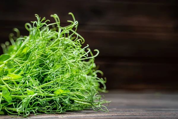 Brotes de guisantes microverdes cortados en una vieja mesa de madera. Concepto de alimentación vegana y saludable. Crecimiento de brotes — Foto de Stock