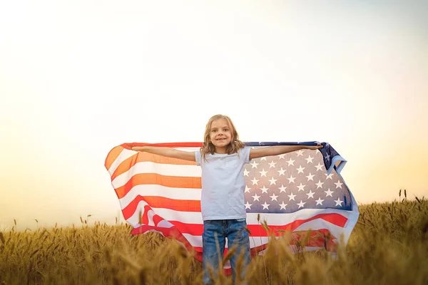 Förtjusande patriotisk flicka klädd i en amerikansk flagga på ett vackert vetefält — Stockfoto