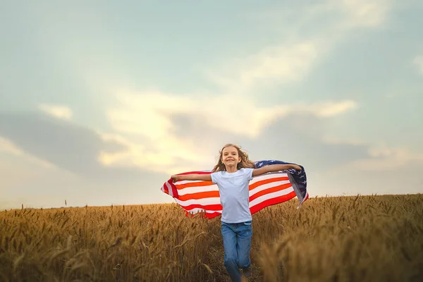 Adorável menina patriótica vestindo uma bandeira americana em um belo campo de trigo — Fotografia de Stock