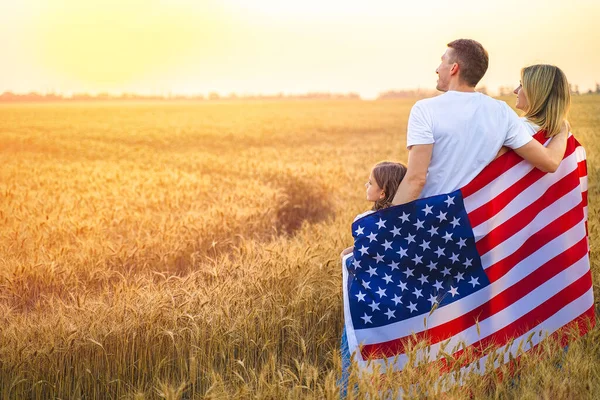 Bakåt bild av en oigenkännlig lycklig familj i vetefält med USA, amerikansk flagga — Stockfoto