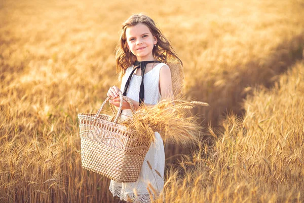 Модное фото маленькой девочки в белом платье и соломенной шляпе на вечернем пшеничном поле — стоковое фото