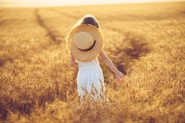 Foto de moda de uma menina em vestido branco e chapéu de palha no campo de trigo da noite — Fotografia de Stock