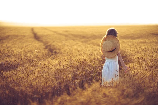 Foto de moda de una niña en vestido blanco y sombrero de paja en el campo de trigo de la noche — Foto de Stock