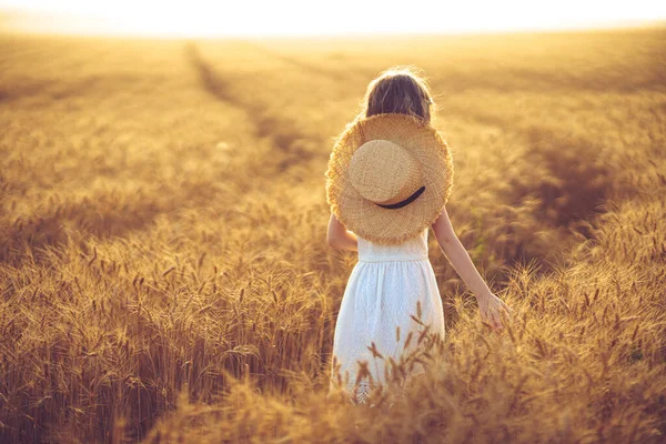 Foto de moda de una niña en vestido blanco y sombrero de paja en el campo de trigo de la noche — Foto de Stock