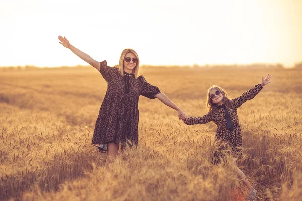 Young mother and her daughter at the wheat field on a sunny day — Stock Photo, Image