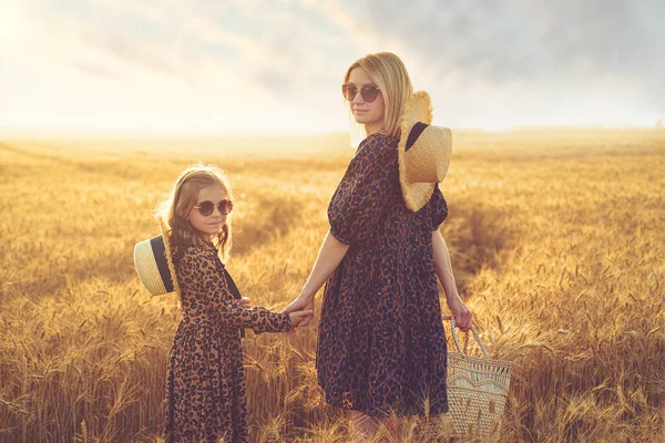 Jovem mãe e sua filha no campo de trigo em um dia ensolarado — Fotografia de Stock