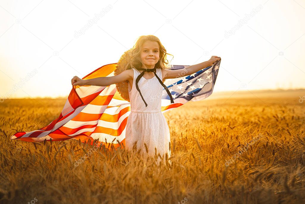 Adorable patriotic girl in white dress wearing an American flag while running in a beautiful wheat field