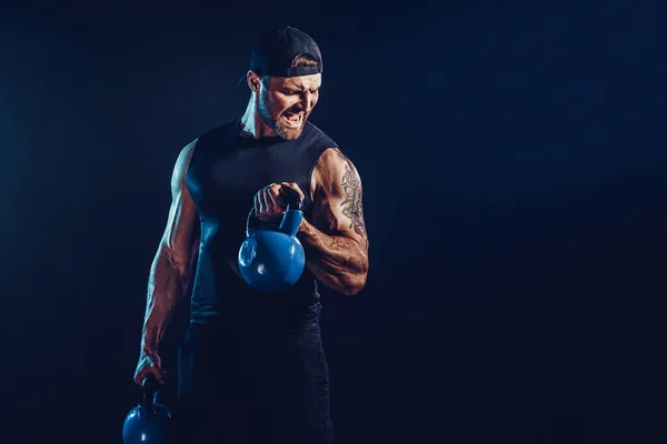 Aggressiv skäggig muskulös kroppsbyggare gör Motion för axelmusklerna, deltoid med kettlebell. — Stockfoto