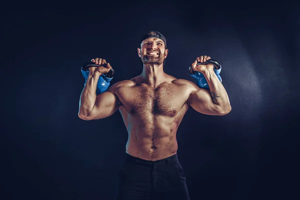 Aggressiver bärtiger muskulöser Bodybuilder macht Übungen für die Schultermuskulatur, Deltamuskel mit Kettlebell. — Stockfoto