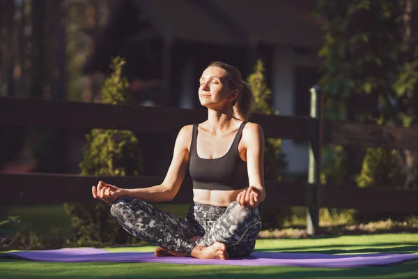 Mujer practicando yoga matutino en el patio trasero. Estilo de vida saludable —  Fotos de Stock