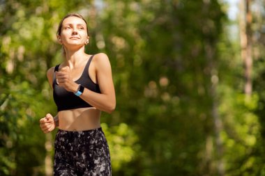 Yeşil bir ormanda koşan güzel bir genç kadın.