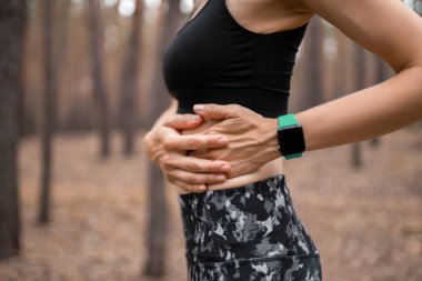 Yan dikiş atan kadın koştuktan sonra yan kramplar geçiriyor. Koşu yaptıktan sonra karın ağrısı çeken bir kadın. Kadın sporcu. Spor, sağlık ve insan kavramı