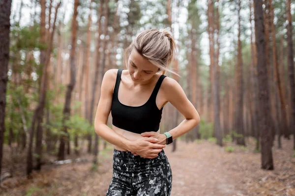 Side stitch woman runner side cramps after running. Jogging woman with stomach side pain after jogging work out. Female athlete. Sport, health and people concept