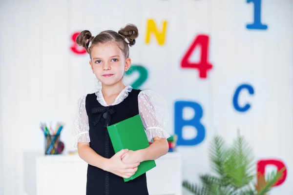 幸せなスマート女の子で学校unifromホールド本と見ますカメラ — ストック写真