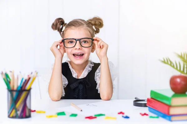 Joyeux élève souriant au bureau. Enfant dans la salle de classe avec crayons, livres. Une gamine de l'école primaire. le premier jour de l'automne. Retour à l'école — Photo