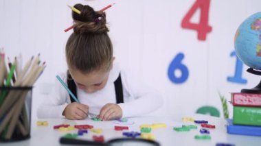 Masadaki mutlu gülümseyen öğrenci. Sınıftaki çocuk kalemlerle, kitaplarla. İlkokuldan bir çocuk. Sonbaharın ilk günü. Okula geri dön.