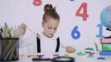 Masadaki mutlu gülümseyen öğrenci. Sınıftaki çocuk kalemlerle, kitaplarla. İlkokuldan bir çocuk. Sonbaharın ilk günü. Okula geri dön.