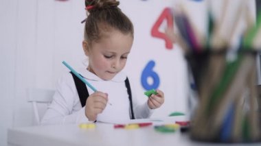 Masadaki mutlu gülümseyen öğrenci. Sınıftaki çocuk kalemlerle, kitaplarla. İlkokuldan bir çocuk. Sonbaharın ilk günü. Okula geri dön.