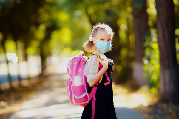 School Girl wearing mask and backpack to protect from coronavirus. Child going school after pandemic over