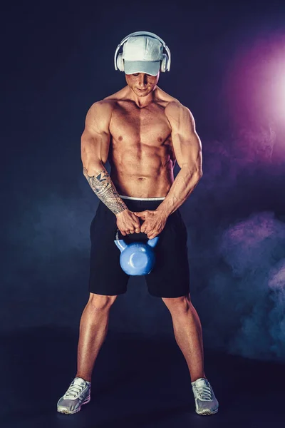 Muscular culturista haciendo ejercicio con Kettlebell. Estudio filmado con humo — Foto de Stock